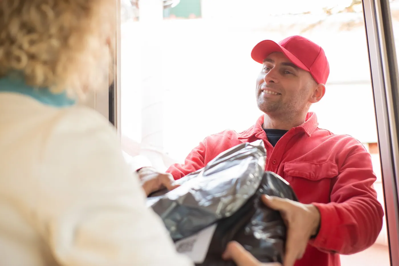 Ein Paketbote übergibt einer Creatorin ein Paket